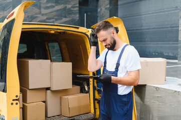 Delivery driver checking cardboard boxes on clipboard next to van
