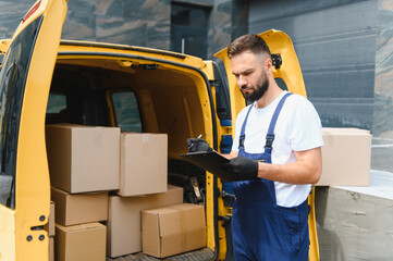 Deliveryman checking cardboard boxes in van using clipboard