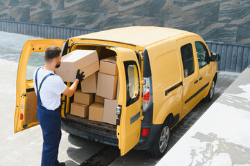Courier loading cardboard boxes into delivery van