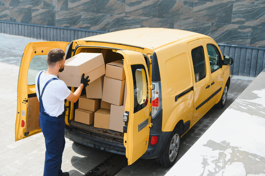 Courier loading cardboard boxes into delivery van