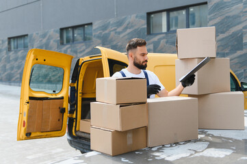 Deliveryman checking cardboard boxes on a clipboard next to his van