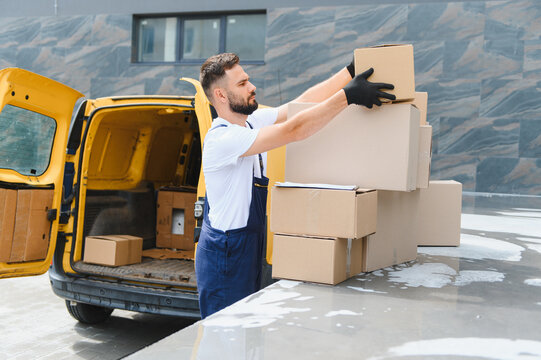 Deliveryman stacking cardboard boxes next to delivery van