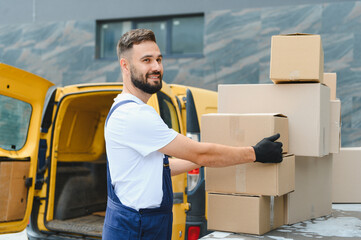 Deliveryman arranging cardboard boxes on top of delivery van