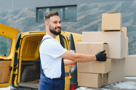 Deliveryman arranging cardboard boxes on top of delivery van