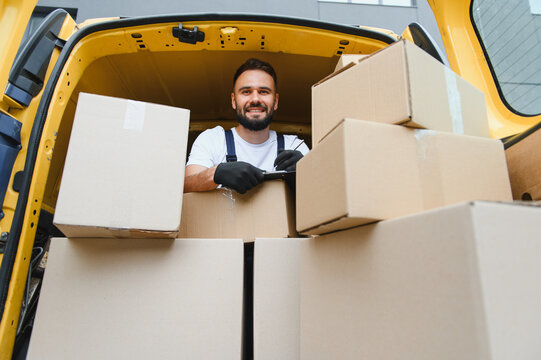 Deliveryman checking packages inside van full of cardboard boxes