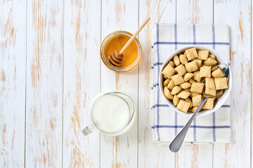 bowl of crispy corn pads with milk and honey on a light kitchen table, top view. Copy space for text.