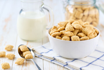 crispy corn pads in a bowl with milk on a white wooden table.