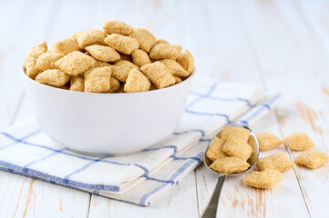 crispy corn pads in a ceramic bowl on a white wooden table, selective focus.
