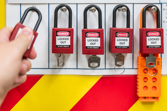 Safety Lockout tagout station with hanging locks with keys and hand of technician putting lock on the station

