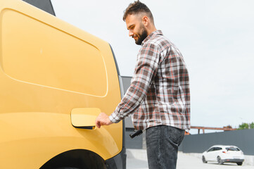 Driver opening fuel tank cap of a yellow van