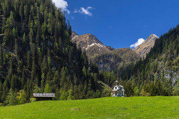 Small chapel and wooden hut standing in a green meadow in the Austrian Alps in Pragraten am...