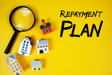 Repayment Plan text with house models and magnifying glass on yellow background