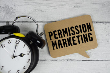 Permission marketing text with alarm clock on wooden background