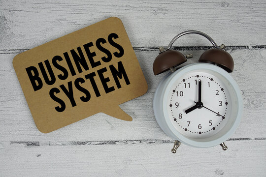 Business system text with alarm clock on wooden background