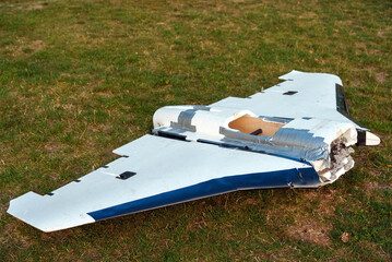 Destroyed Russian Gerbera UAV lying on grass. Decoy drone used as a false aerial target to overload air defense systems, damaged and downed unmanned aircraft wreckage.