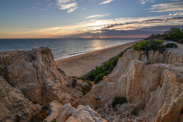 Scenic sunset over cliffs, pine forest, and golden beach in Mazagon, Huelva, Spain. Tranquil seascape ideal for travel, nature, and landscape concepts.