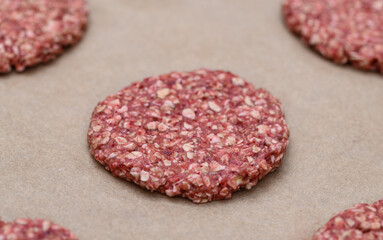 A macro close-up of a raw oatmeal cookie with raspberries before baking, lying on brown baking paper.