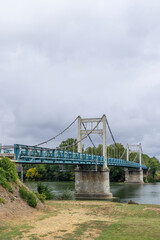 Fototapeta premium Suspension bridge crossing Garonne river in Auvillar, France, under cloudy sky