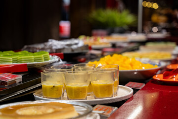 Close up of assorted desserts and pudding glasses on buffet table.