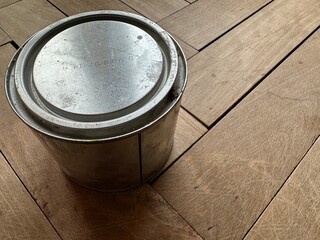 Wood wax for parquet care — a jar on a wooden floor. Concept of interior care, eco-friendly protection, and durability.