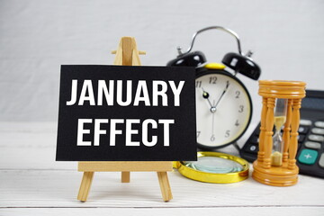 January Effect text with magnifying glass and calculator on wooden background