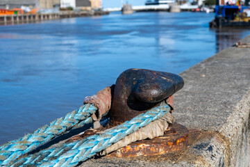 Close and selective focus of rope looped around a mooring cleat on the harbour wall in Great Yarmouth, Norfolk