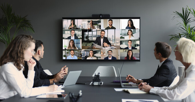 Group of diverse businesspeople gathered in boardroom engaging in videoconference - Powered by Adobe