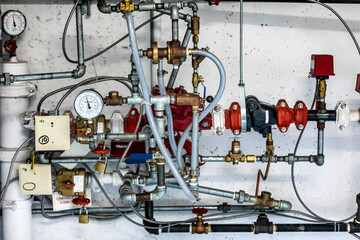Complex network of plumbing pipes and valves in a commercial facility showing intricate connections and pressure gauges