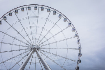 Giant Ferris wheel towers against a cloudy sky in a bustling amusement park during evening hours