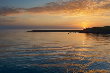 Naklejka premium Serene ocean sunset with vibrant orange and yellow clouds reflecting on calm water