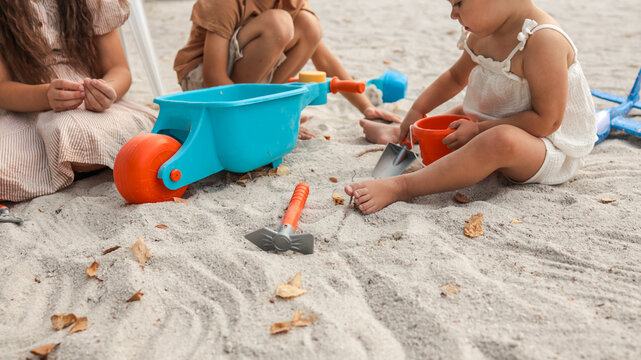 Children playing with toys in the sand at the beach on a sunny day.