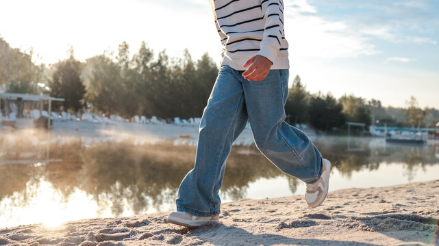 Person walking on the beach near a lake on a sunny day - Powered by Adobe