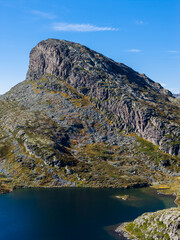 Dramatic close-up of a rugged mountain and tranquil lake.