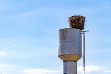Soviet-era water tower with stork nest symbolizing harmony between industry and nature in Belarusian countryside. Minsk Region, Belarus.