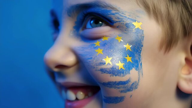 Close-up video of child with European Union flag face paint blinking and smiling, symbolizing Europe, democracy, unity and hope, patriotic portrait with emotional expression in blue and gold