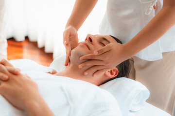 Caucasian man enjoying relaxing anti-stress head massage and pampering facial beauty skin recreation leisure in dayspa modern light ambient at luxury resort or hotel spa salon. Quiescent