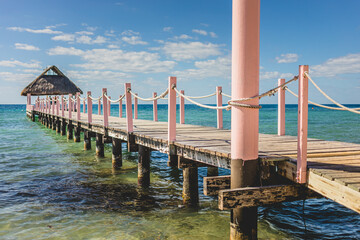 Colorful wooden pier extends over calm turquoise waters under a vibrant blue sky with scattered clouds
