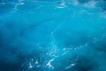 Vibrant turquoise ocean waves gently lapping against the shoreline under bright sunlight during midday