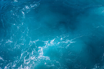 Waves crashing against a rocky shoreline under bright sunlight in a tropical paradise