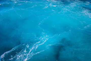Vibrant ocean waves create a stunning blue tapestry near coastal shores during a sunny afternoon