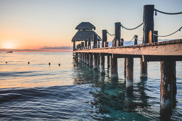 Sunset view from a wooden pier extending into calm waters off a tropical shore