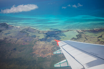 Scenic aerial view of tropical coastline with vibrant blue waters during daytime flight