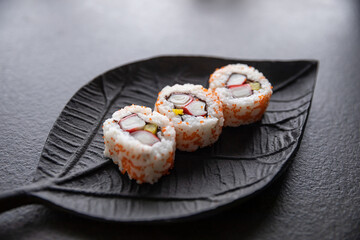 Zestaw sushi na czarnej tacy w kształcie liścia Assorted sushi on a black leaf-shaped tray