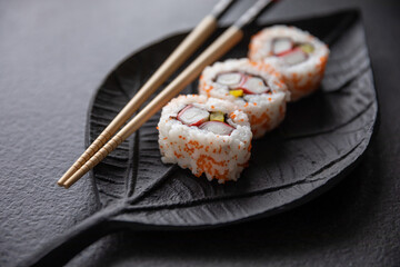 Zestaw sushi na czarnej tacy w kształcie liścia Assorted sushi on a black leaf-shaped tray