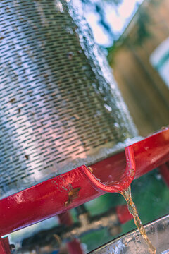 Apple Juice draining from a metal hydropress strainer into a bowl during a food preparation process
