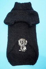 on a blue background lies a knitted black sweater to dogs pets for dogs, turned over . handmade