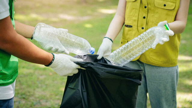 Volunteers collect plastic bottles for recycling in a green park promoting environmental sustainability community cleanup efforts - Powered by Adobe