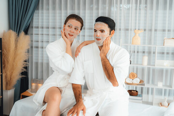 Serene modern daylight ambiance of spa salon, couple customer indulges in rejuvenating with facial skincare mask. Facial skin treatment and beauty cosmetology procedure for face. Quiescent