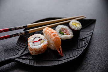 Zestaw sushi na czarnej tacy w kształcie liścia Assorted sushi on a black leaf-shaped tray