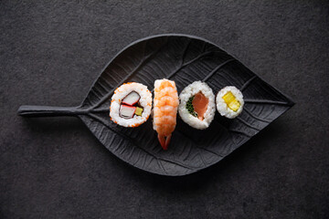 Zestaw sushi na czarnej tacy w kształcie liścia Assorted sushi on a black leaf-shaped tray